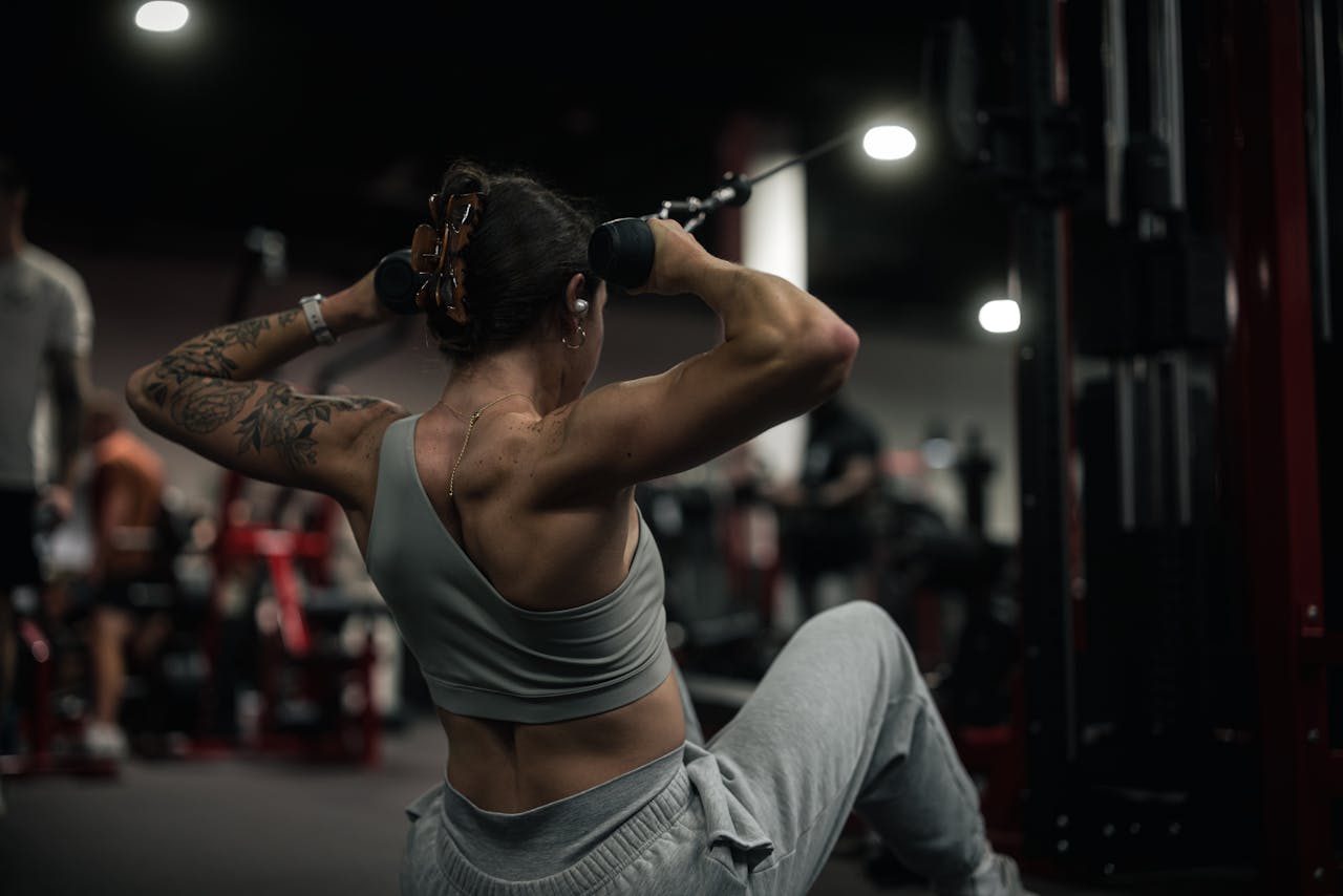 Woman performs strength training with a cable machine in a modern gym setting.